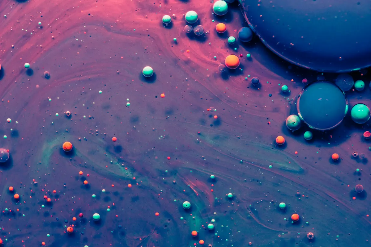 Ink and oil bubbles drifting through blue and violet liquid